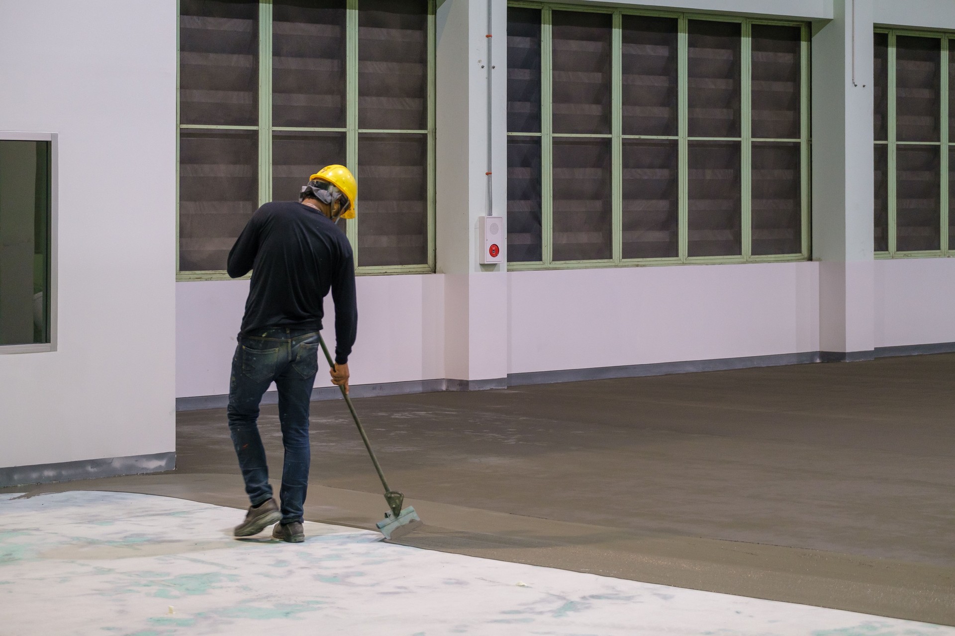 Construction worker using trowel spreading moisture blocking epoxy primer for Self-leveling method of epoxy floor finishing work